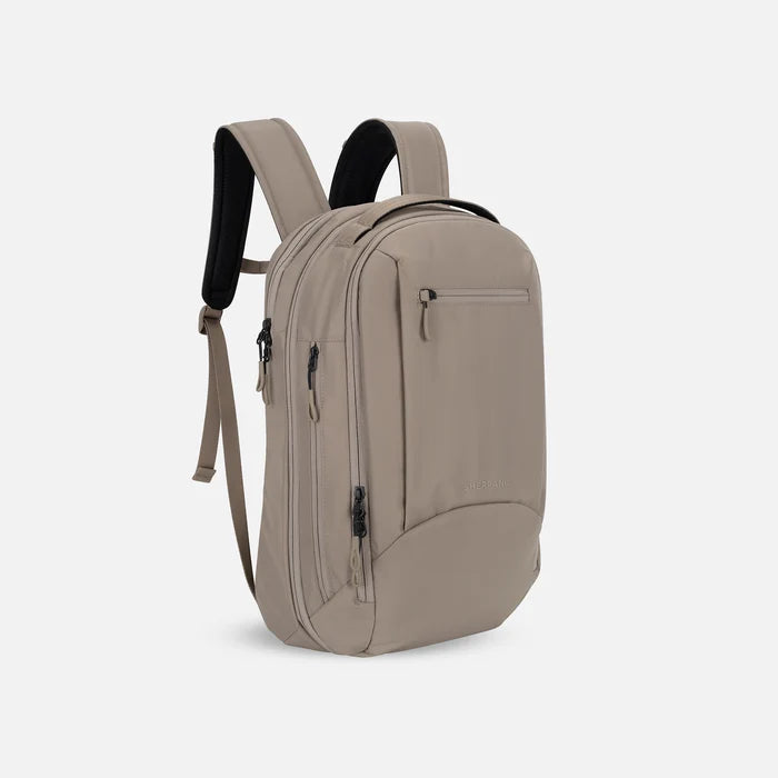 A Sherpani Crew Dune Travel Backpack, 3/4 view showing lockable zippers and different straps against a white background. #color_dune-tan
