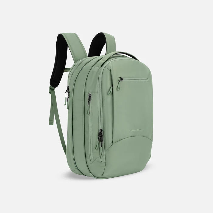 A Sherpani Crew Olivine Travel Backpack, 3/4 view showing lockable zippers and the extender pocket against a white background #color_olivine-green