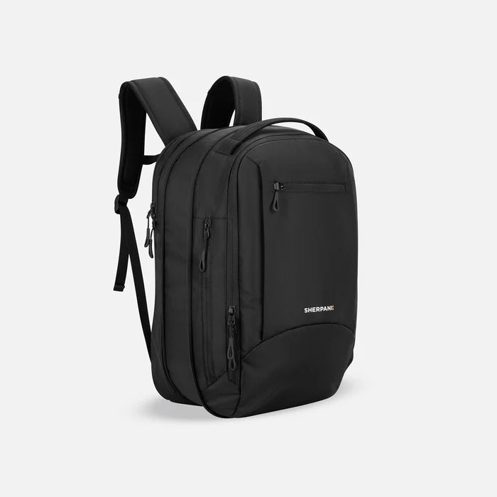 A Sherpani Crew Raven Black Travel Backpack, 3/4 view showing lockable zippers and the extender pocket against a white background. #color_raven-black