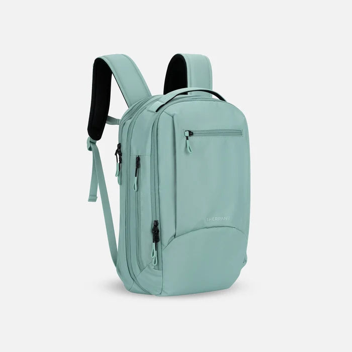 A Sherpani Crew Surf Blue Travel Backpack, 3/4 view showing lockable zippers and different straps against a white background. #color_surf-blue