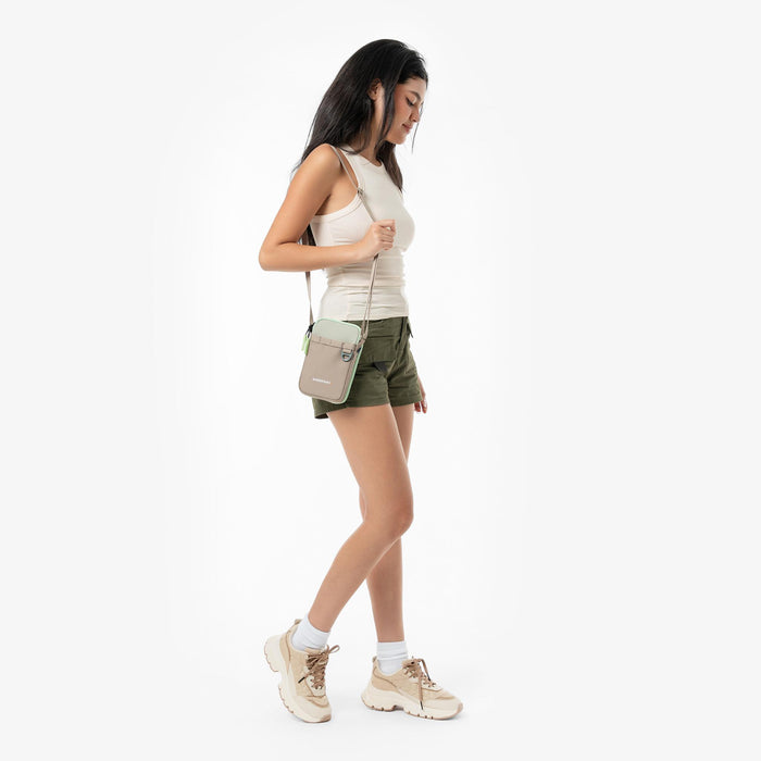 Woman wearing a Sherpani Cruz Desert Aloe Small Crossbody against white backdrop.  #color_desert-aloe