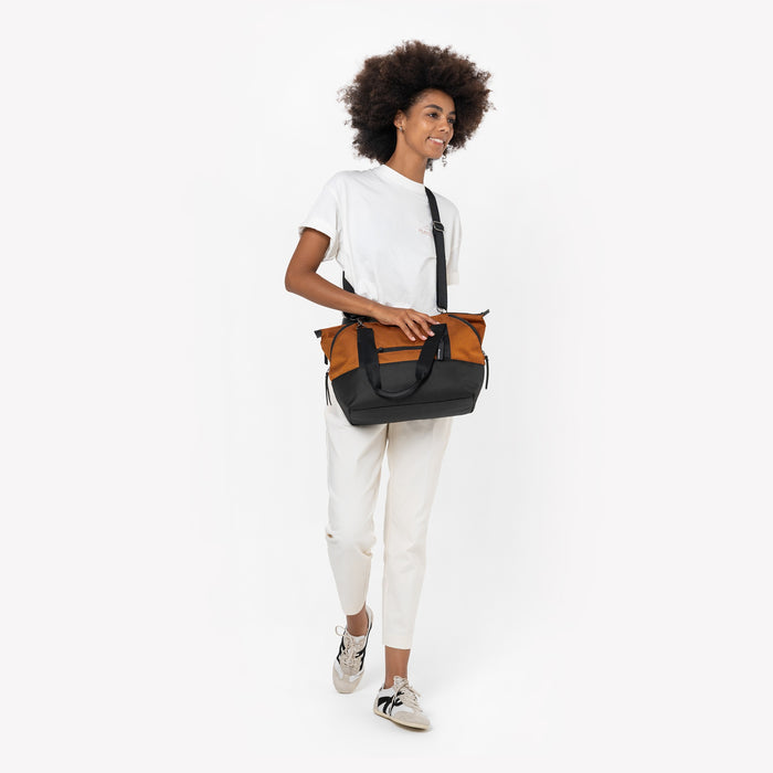 Woman wearing a Sherpani Eclipse Morocco Expandable Tote by crossbody strap against white backdrop. #color_morocco