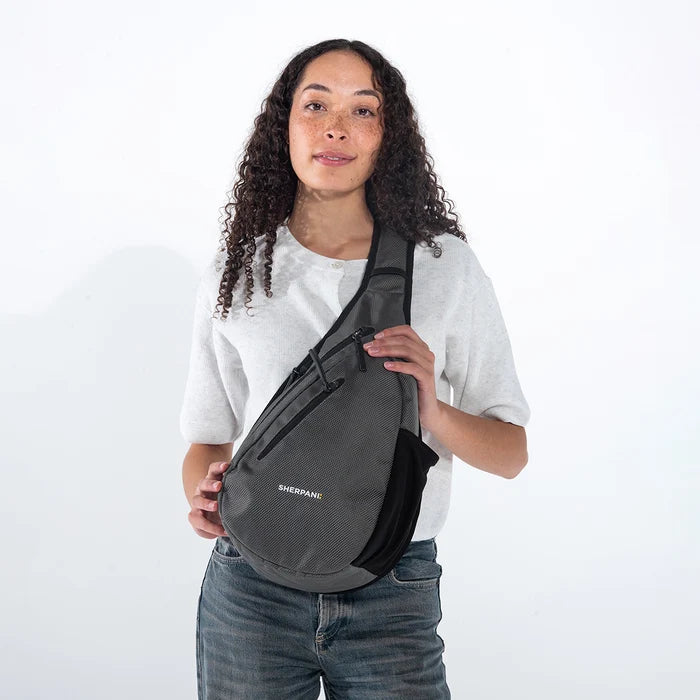 Woman wearing a Sherpani Esprit Granite Anti-theft Sling on her front against white backdrop.  #color_granite-grey