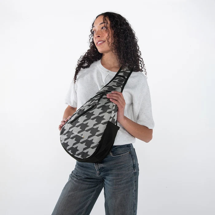 Woman wearing a Sherpani Esprit Houndstooth Anti-theft Sling on her front against white backdrop.  #color_houndstooth-print