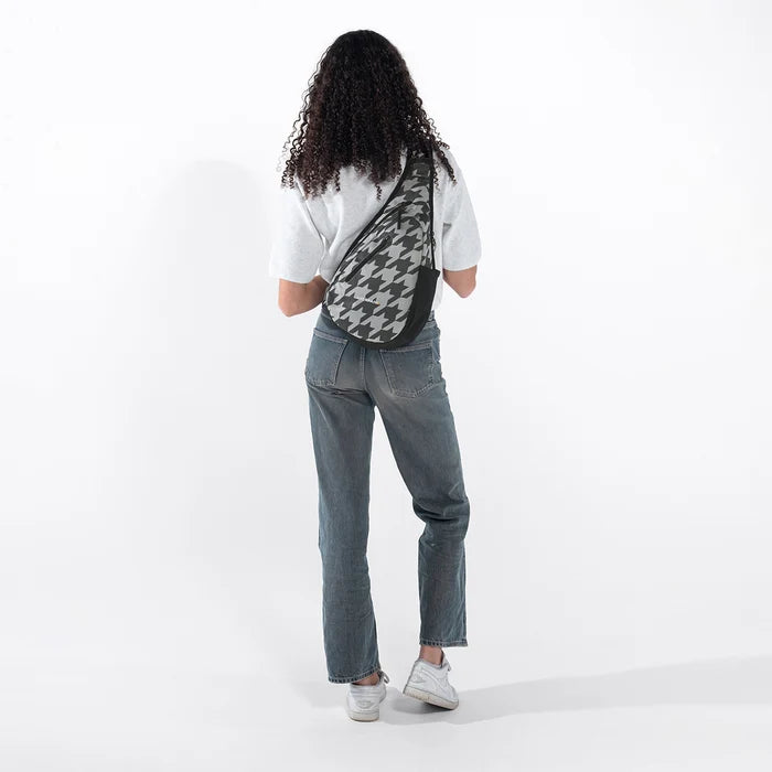 Woman wearing a Sherpani Esprit Houndstooth Anti-theft Sling on her back against white backdrop. #color_houndstooth-print