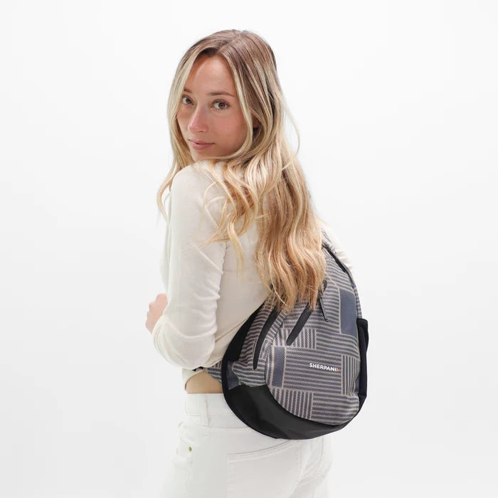Woman wearing a Sherpani Esprit Passport Anti-theft Sling on her back against white backdrop. #color_passport-print