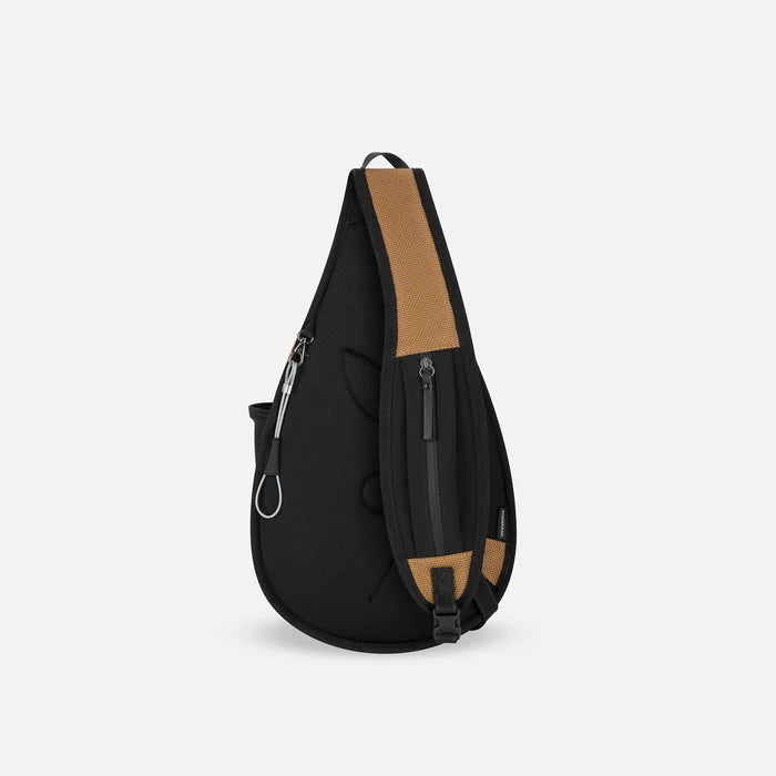 A Sherpani Esprit Sand Anti-theft Sling Bag, back view showing the strap pocket and the chair lock on a white background. #color_sand-tan