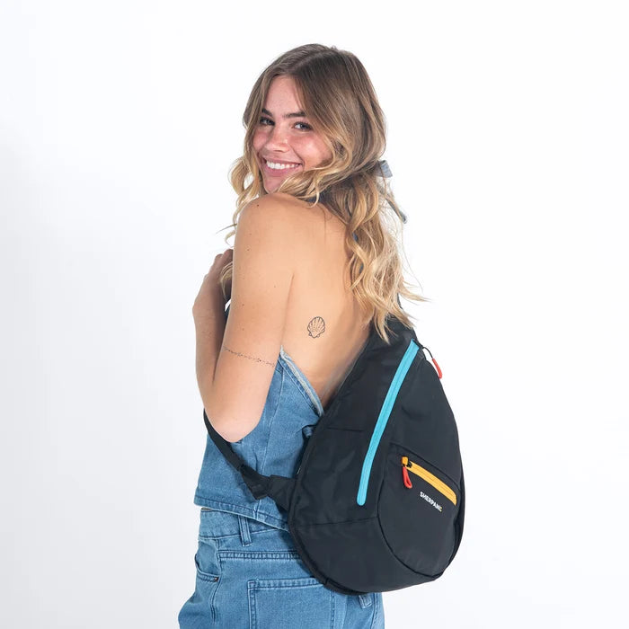 Woman wearing a Sherpani Esprit Chromatic Black Sling on her back against white backdrop. #color_chromatic-black