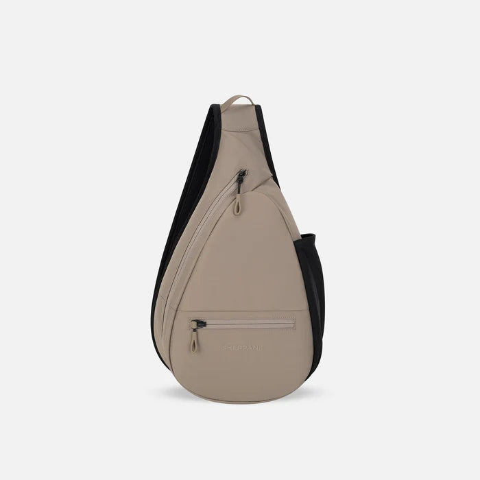 A Sherpani Esprit Dune Sling, front view showing strap & lockable pockets on white backdrop.  #color_dune-tan