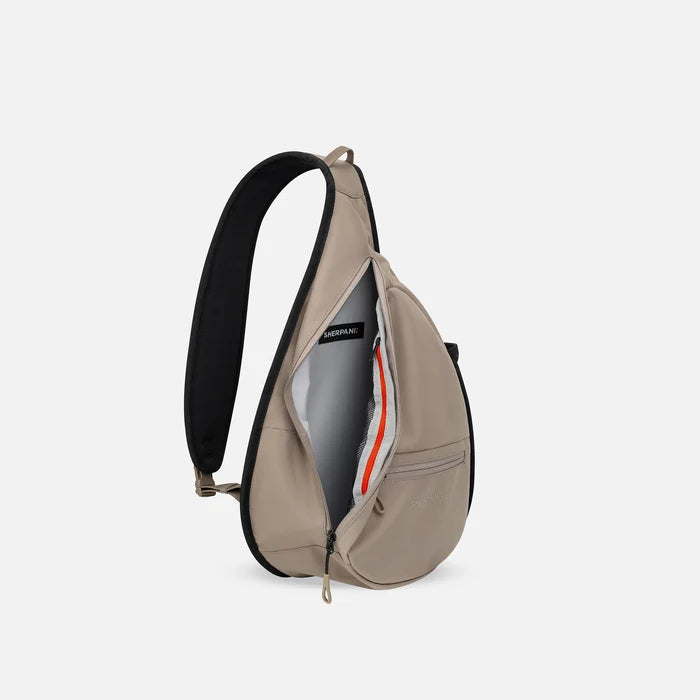 A Sherpani Esprit Dune Sling Bag, side view showing inside of main pocket with a sleeve on a white background.  #color_dune-tan