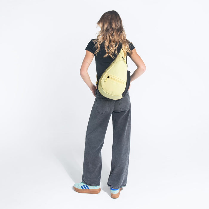 Woman wearing a Sherpani Esprit Sol Yellow Sling Bag against white background.  #color_sol-yellow