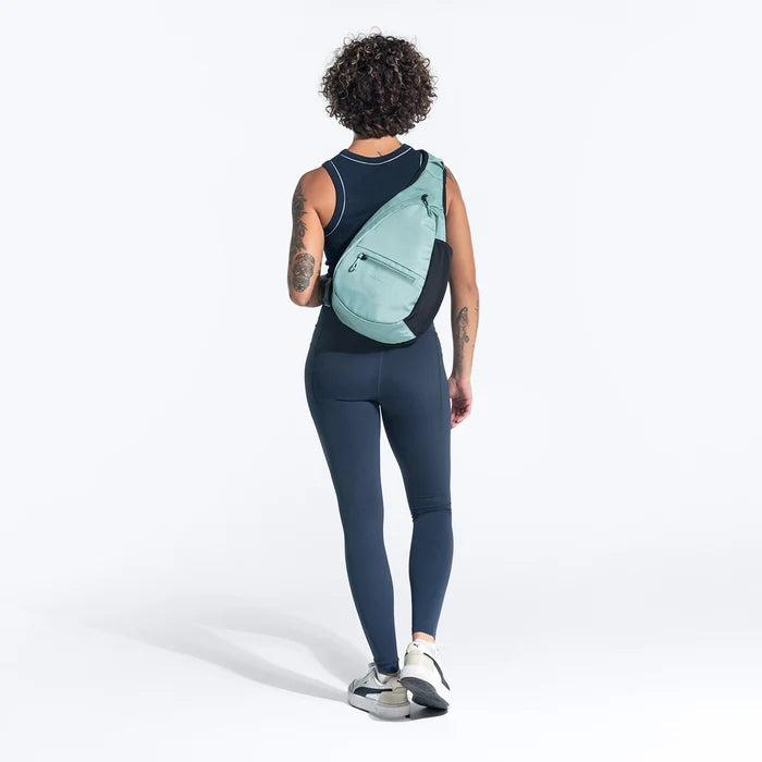 Woman wearing a Sherpani Esprit Surf Blue Sling on her back against white backdrop. #color_surf-blue