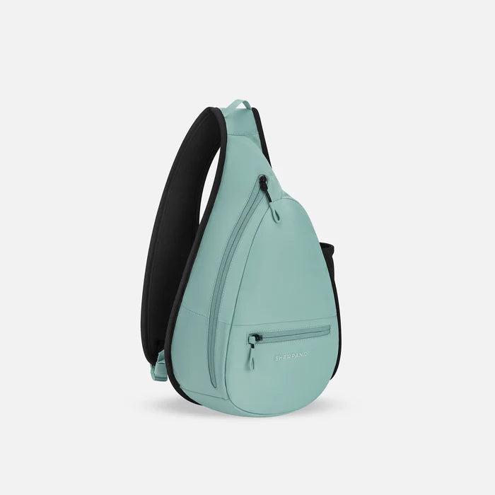 A Sherpani Esprit Surf Blue Sling, 3/4 view showing strap & lockable pockets on white backdrop. #color_surf-blue