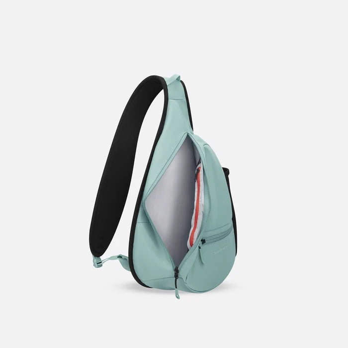 A Sherpani Esprit Surf Blue Sling Bag, side view showing inside of main pocket with a sleeve on a white background.  #color_surf-blue