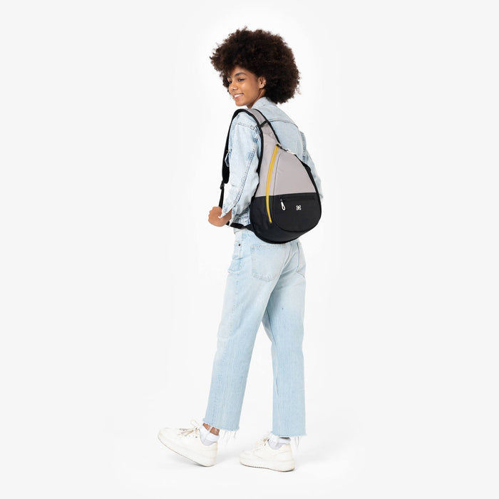 Woman wearing a Sherpani Esprit Wasabi Stone Sling Bag against white background.  #color_wasabi-stone-heritage