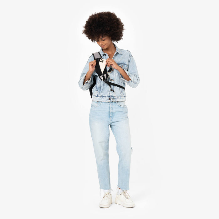 Woman placing a phone in the strap pocket on a Sherpani Esprit Wasabi Stone Sling Bag against white background.  #color_wasabi-stone-heritage