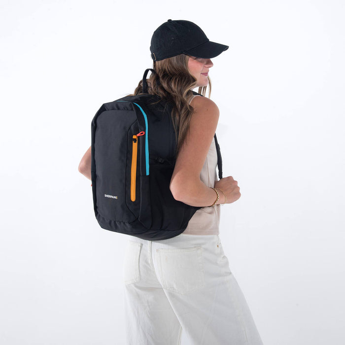 Woman wearing a Sherpani Getaway Chromatic Black Travel Backpack on her back against white backdrop.  #color_chromatic-black