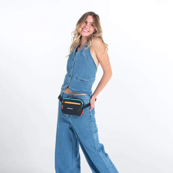 Woman wearing a Sherpani Hyk Chromatic Black Hip Pack on her hip against white backdrop.   #color_chromatic-black