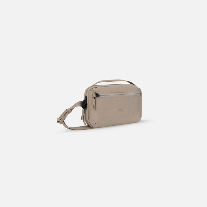 A Sherpani Hyk Dune Hip Pack, 3/4 view showing pocket and straps on white backdrop. #color_dune-tan