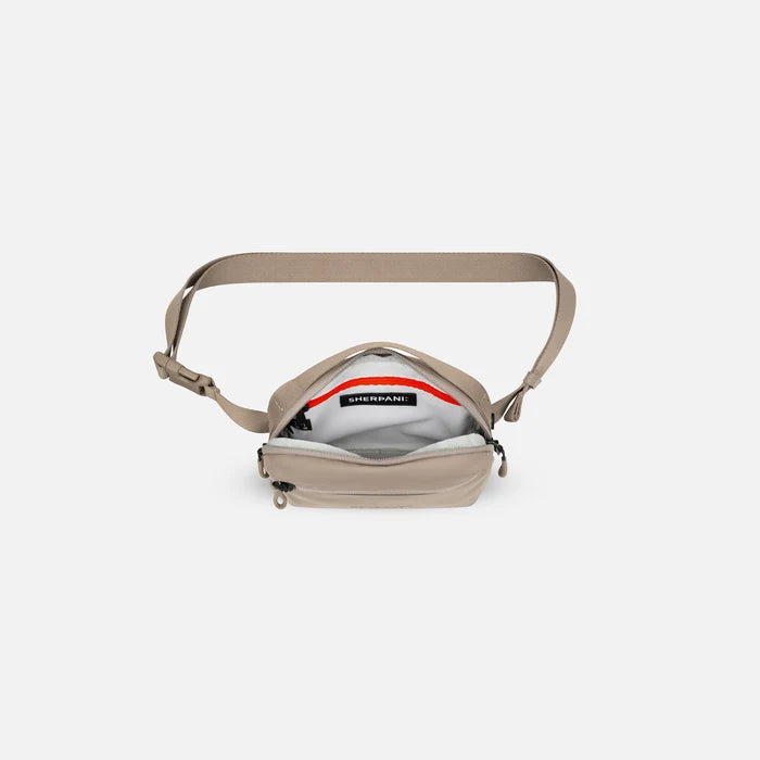 A Sherpani Hyk Dune Hip Pack, above view showing inside of main pocket on white backdrop. #color_dune-tan