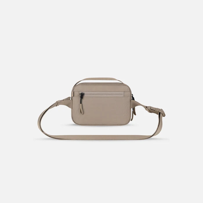 A Sherpani Hyk Dune Hip Pack, back view showing pocket and straps on white backdrop. #color_dune-tan