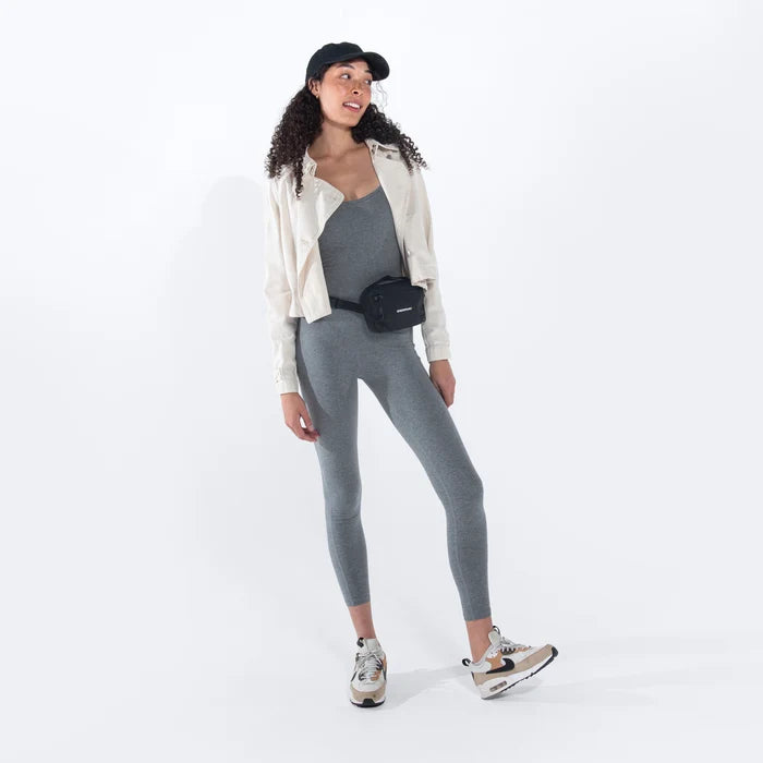 Woman wearing a Sherpani Hyk Raven Black Hip Pack on her hip against white backdrop.  #color_raven-black
