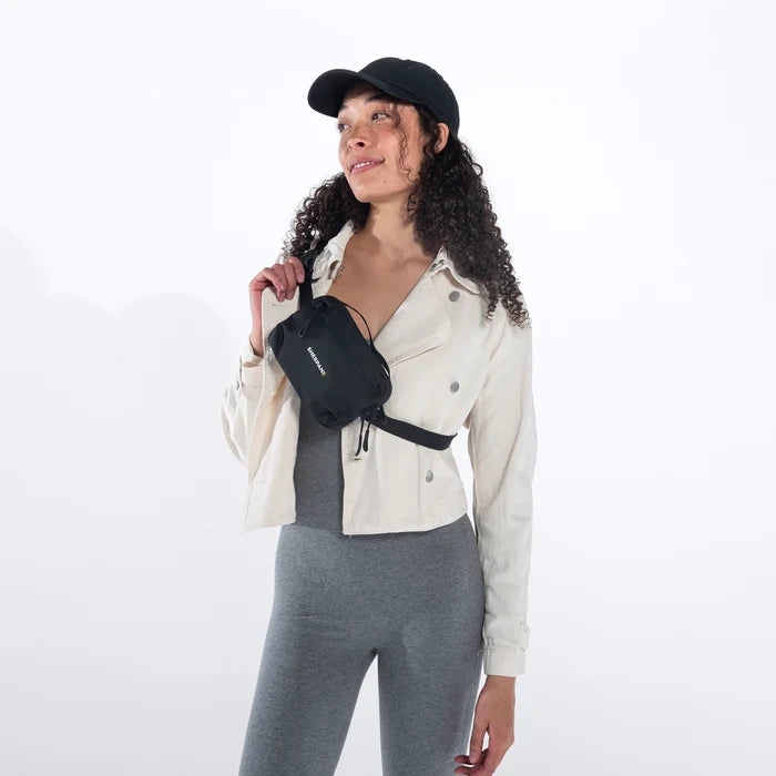 Woman wearing a Sherpani Hyk Raven Black Hip Pack across her body against white backdrop.  #color_raven-black