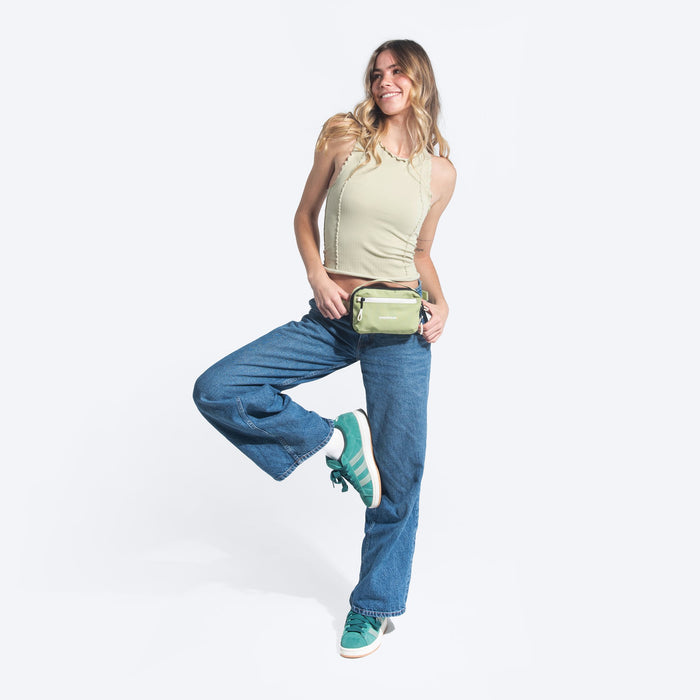 Woman wearing a Sherpani Hyk Palm Green Hip Pac on her hip against white backdrop.  #color_palm-green