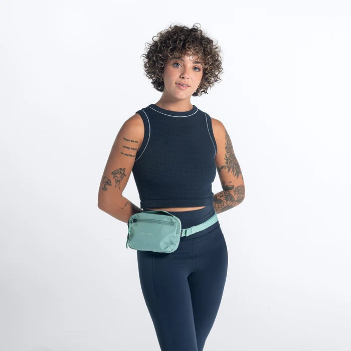 Woman wearing a Sherpani Hyk Surf Blue Hip Pack on her hip against white backdrop. #color_surf-blue
