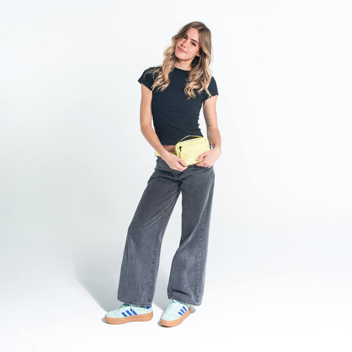Woman wearing a Sherpani Hyk Sol Yellow Hip Pac on her hip against white backdrop.  #color_sol-yellow