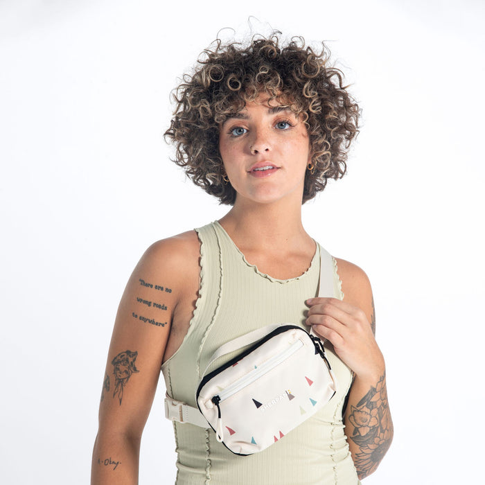 Woman wearing a Sherpani Hyk Terrazzo Print Hip Pack across her body against white backdrop.  #color_terrazzo-print