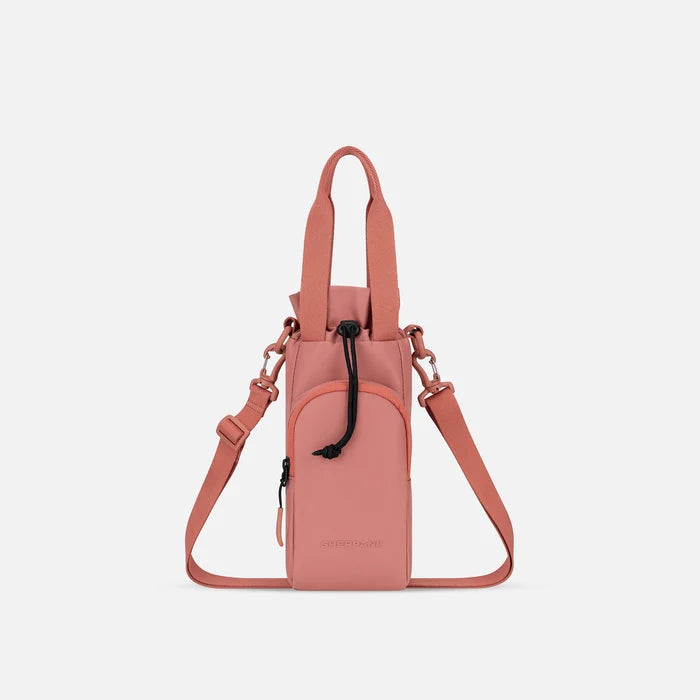 A Sherpani Izzie Desert Pink Water Bottle Crossbody, front view showing strap and front pocket on white background.  #color_desert-pink