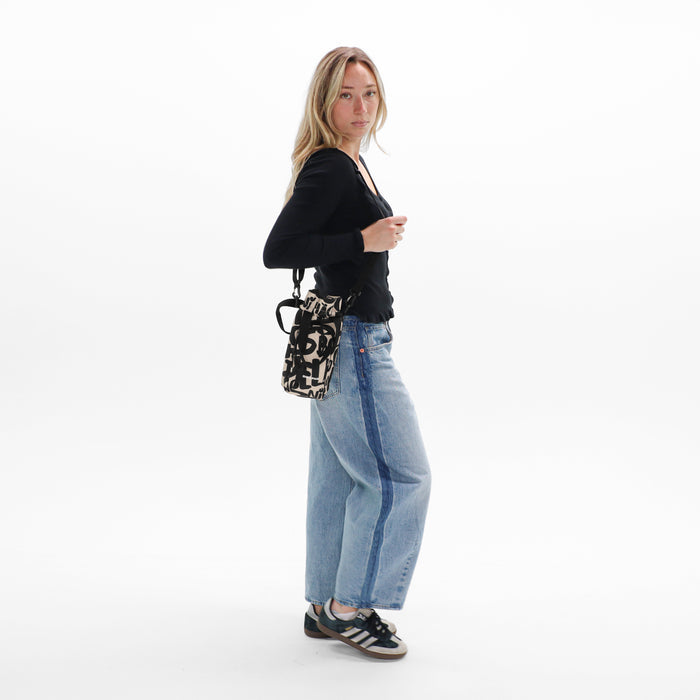 Woman wearing a Sherpani Izzie Ciao Water Bottle Crossbody on white background.  #color_ciao-print