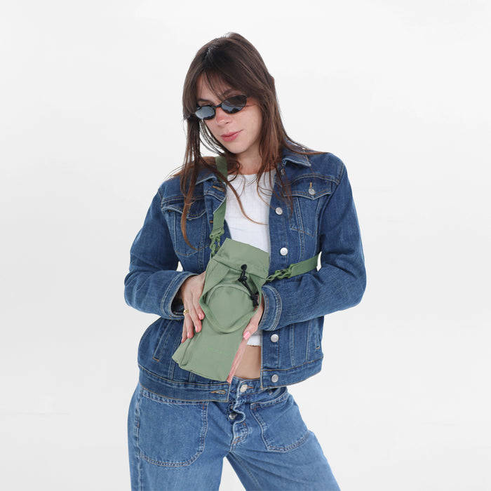 Woman wearing a Sherpani Izzie Olivine Water Bottle Crossbody on white background. #color_olivine-green