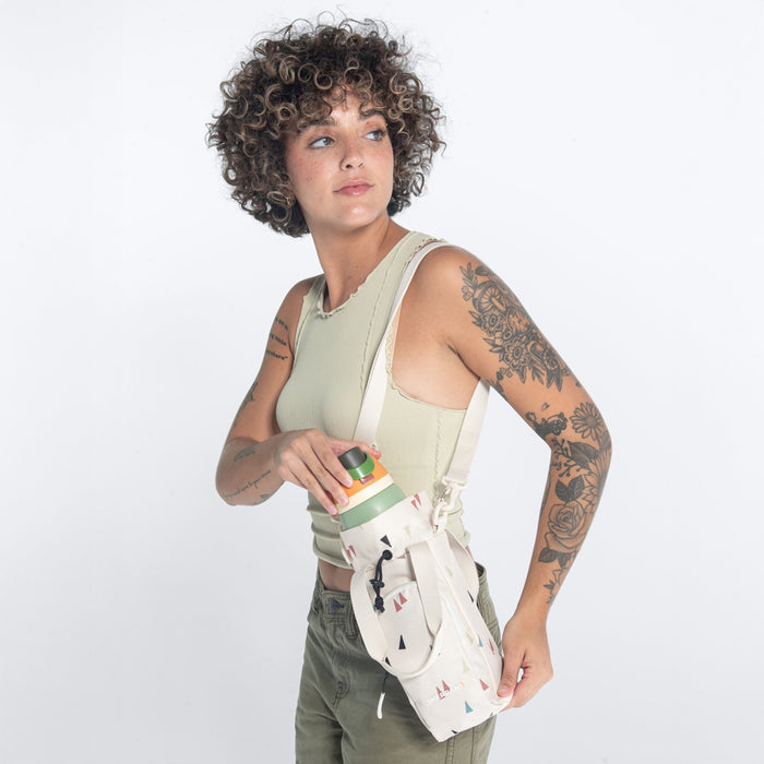 Woman wearing a Sherpani Izzie Terrazzo Print Water Bottle Crossbody by crossbody strap on white background.  #color_terrazzo-print