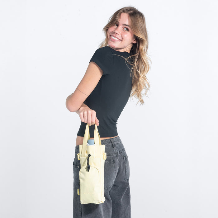Woman holding a Sherpani Izzie Sol Yellow Water Bottle Crossbody by handheld straps on white background. #color_sol-yellow