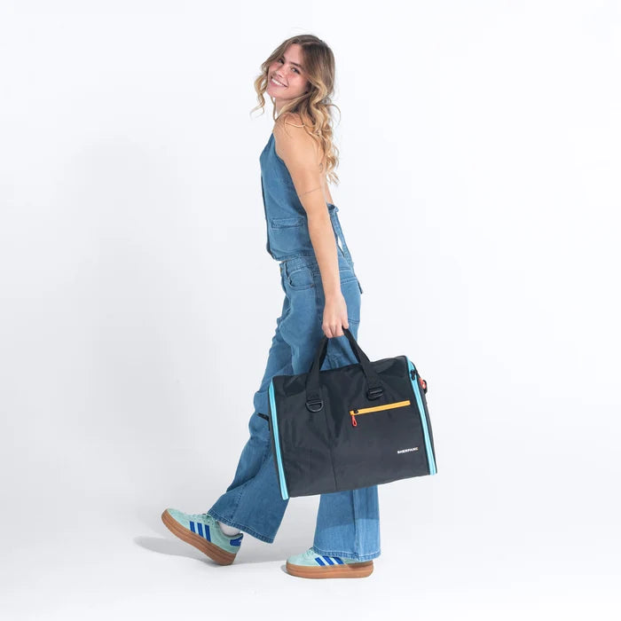 Woman holding a Sherpani Jaunt Chromatic Black Garment Duffle against white backdrop. #color_chromatic-black