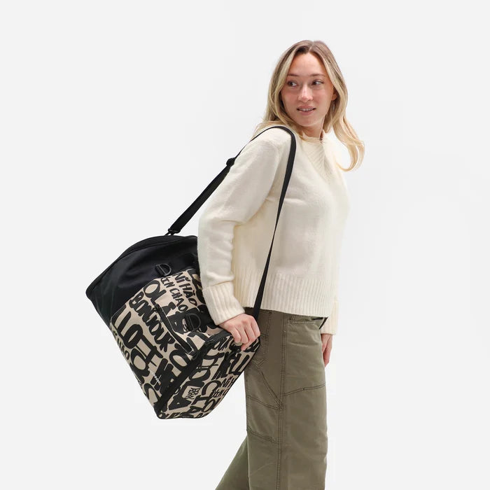 Woman wearing a Sherpani Jaunt Ciao Garment Duffle by crossbody strap against white backdrop. #color_ciao-print