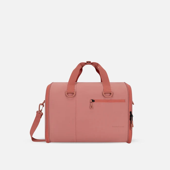 A Sherpani Jaunt Desert Pink Garment Duffle, front view showing straps & lockable pocket on white backdrop.   #color_desert-pink