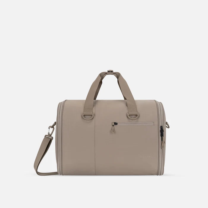 A Sherpani Jaunt Dune Garment Duffle, front view showing straps & lockable pocket on white backdrop. #color_dune-tan