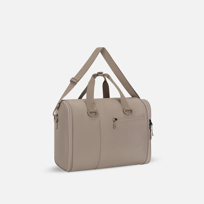 A Sherpani Jaunt Dune Garment Duffle, 3/4 view showing two strap options on white backdrop. #color_dune-tan