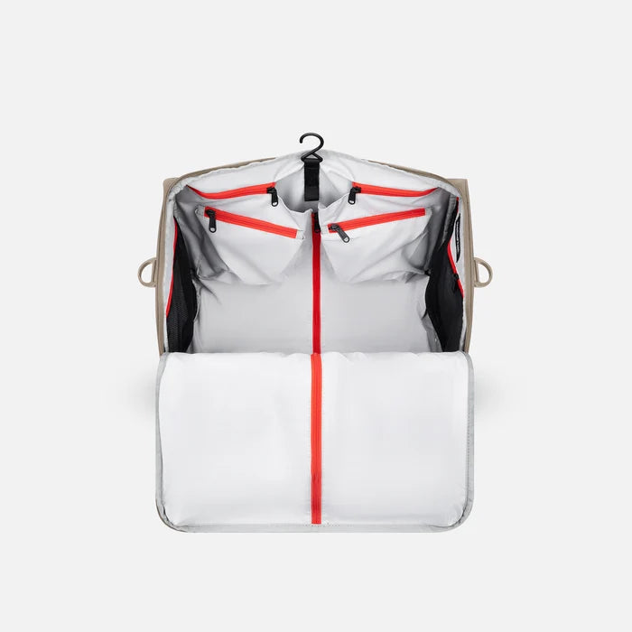 A Sherpani Jaunt Dune Garment Duffle, back view showing straps & luggage strap on white backdrop.   #color_dune-tan