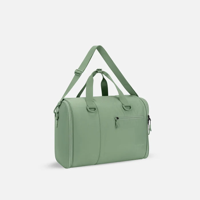 A Sherpani Jaunt Olivine Garment Duffle, 3/4 view showing two strap options on white backdrop. #color_olivine-green