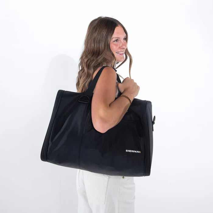 Woman wearing a Sherpani Jaunt Raven Black Garment Duffle against white backdrop. #color_raven-black