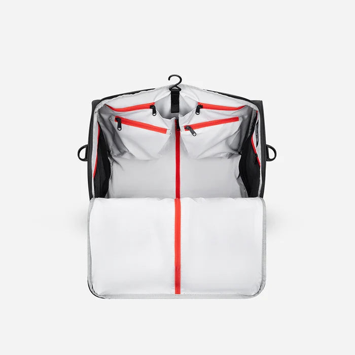 A Sherpani Jaunt Raven Black Garment Duffle, above mostly zipped view showing inside main pockets on white backdrop.  #color_raven-black