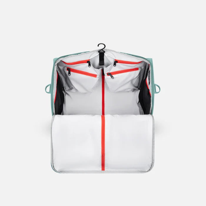 A Sherpani Jaunt Surf Blue Garment Duffle, above mostly zipped view showing inside main pockets on white backdrop.  #color_surf-blue
