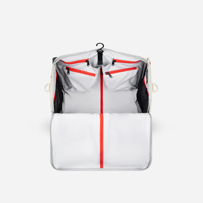 A Sherpani Jaunt Terrazzo Print Garment Duffle, above mostly zipped view showing inside main pockets on white backdrop.  #color_terrazzo-print
