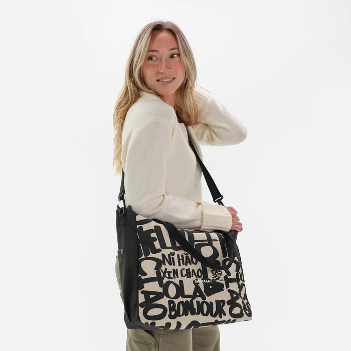 A woman wearing a Sherpani Jetsetter Ciao Travel Tote Bag by the crossbody strap on white backdrop.  #color_ciao-print