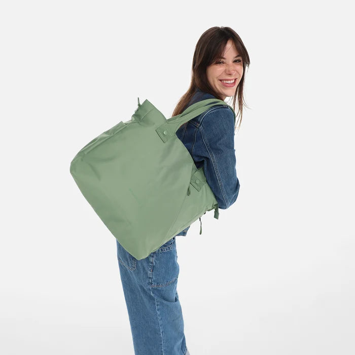 A woman wearing a Sherpani Jetsetter Olivine Travel Tote Bag on white backdrop. #color_olivine-green