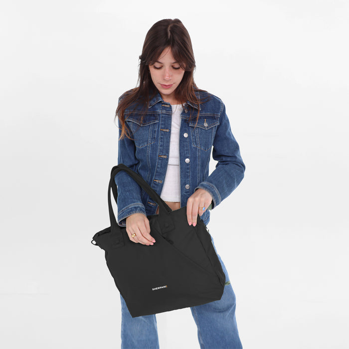 A woman wearing a Sherpani Jetsetter Raven Black Travel Tote Bag on white backdrop. #color_raven-black